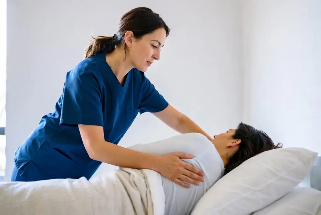 ممرضة تقوم بتقليب مريضة في الفراش